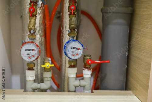 Fotografía Hot and cold water meters with pipes, valves and hoses are installed in a residential plumbing cabinet