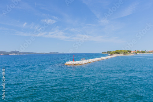 Sticker Stone breakwater pier extending into blue sea on sunny summer day