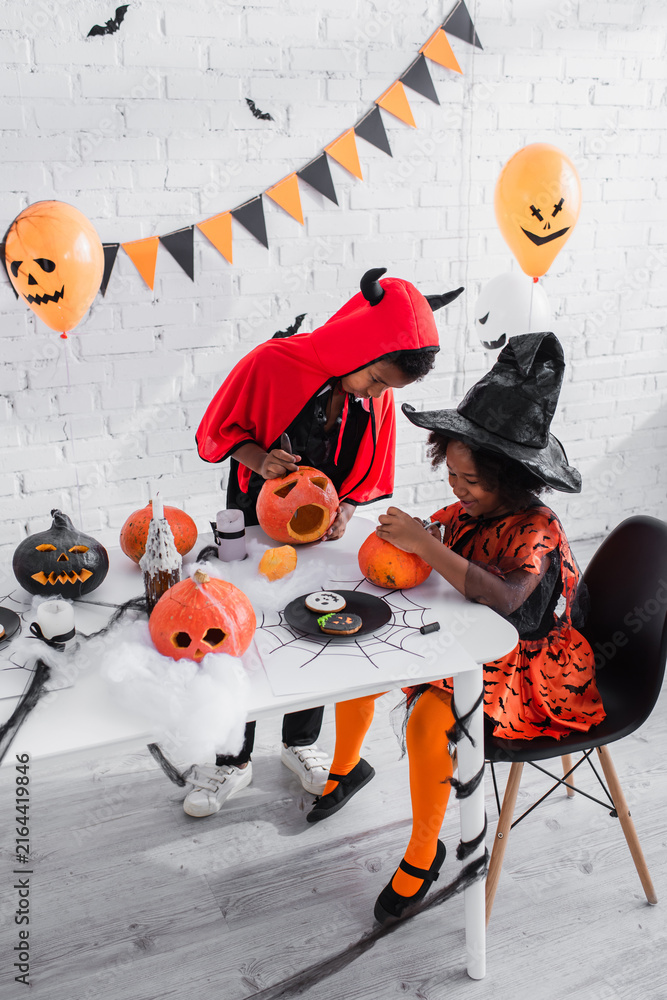 Fototapeta premium Little siblings share joyful moments while creating spooky fun for Halloween