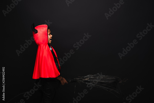 Konstfotografi Little boy enjoys Halloween fun in a vibrant devil costume with a broomstick