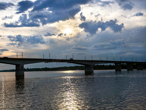 Принти на полотні A picturesque waterscape featuring a long bridge and a sunlit path across the river