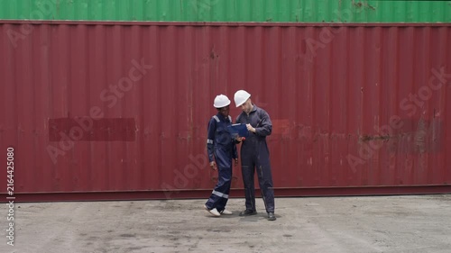 Shipping engineers discussing logistics at a container yard for efficiency.