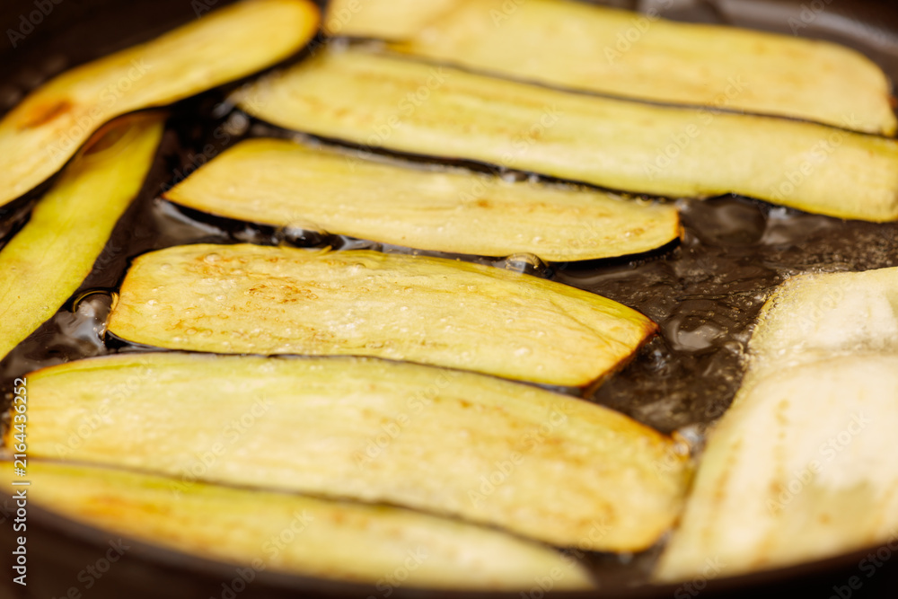 Naklejka premium Eggplant slices sizzle in hot oil