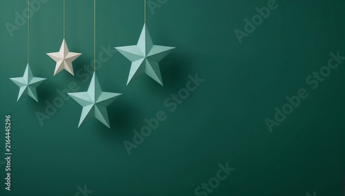 Decorative teal and white star ornaments hanging against a dark teal background, creating a festive and minimalist aesthetic