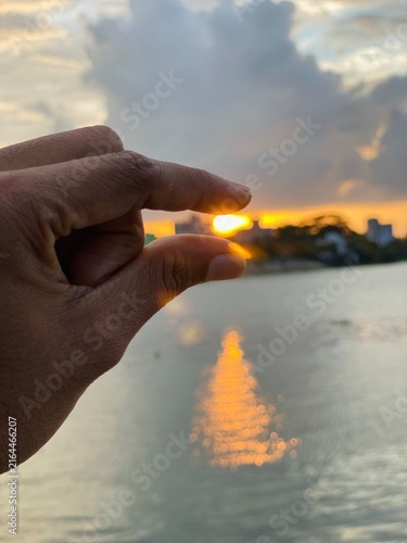 Hand Pinching Setting Sun Creative Forced Perspective Over Water Sunset