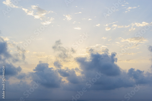 Foto Soft sunlight and crepuscular rays filtering through dark, fluffy cumulus clouds above a serene ocean horizon in Gran Alacant, Alicante, Spain