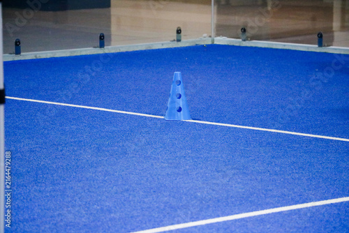 Blue marker cone on a synthetic turf court during a padel tennis ball training session