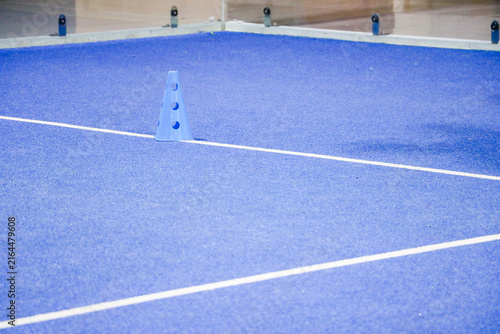 Blue marker cone on a synthetic turf court during a padel tennis ball training session