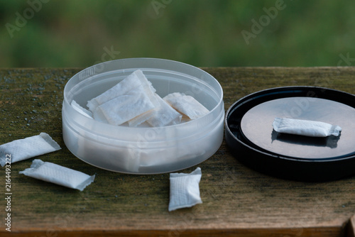 Konstfotografi nicotine pouches white snus container on old wooden board with natural green bac
