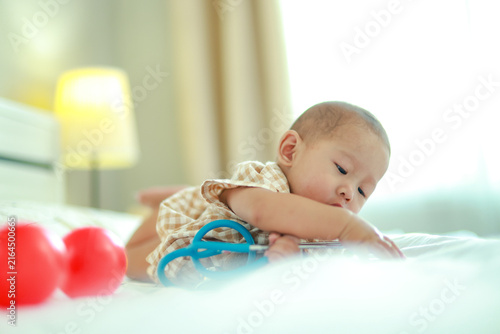 Foto Little boy, an Asian baby, crawls and plays on his bed at home his innocence and adorable cuteness making him look at a medical stethoscope as a fun toy