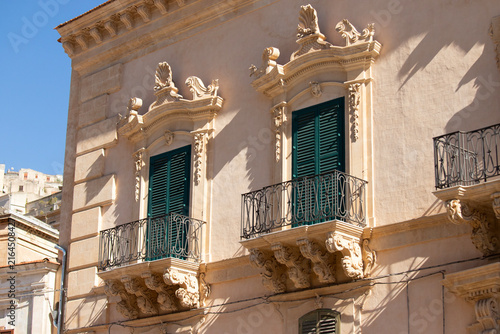 Canvastavla Modica, Italy; 1st August 2026: Baroque architectural detail with carved grotesque face and ornate stonework on a balcony in Sicily