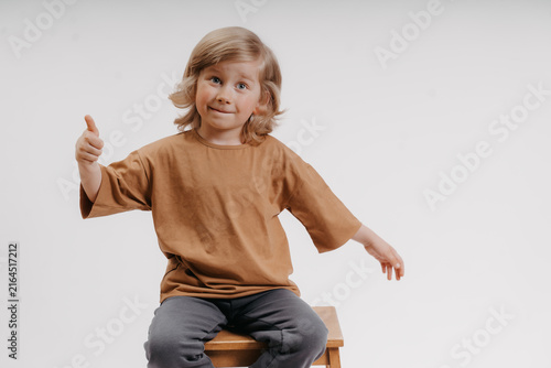 cute little boy in a black T-shirt is giving the thumbs up gesture