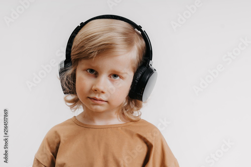 portrait of cute 4-5 year old boy with headphones on his head on white background