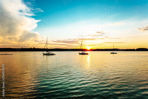 landscape of a peaceful sunset over Wörthsee lake, near Ammersee in Bavaria, Germany, Europe. Dramatics clouds, Dark, heavy storm clouds gather. Radiant golden sunbeams burst through in the cloud