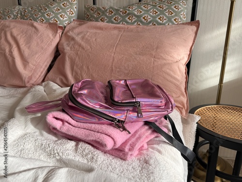 Baby backpack with folded clothes in bed close up