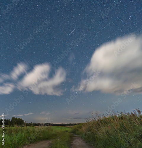 Satellite trails across a starry night sky over rural Latvia.