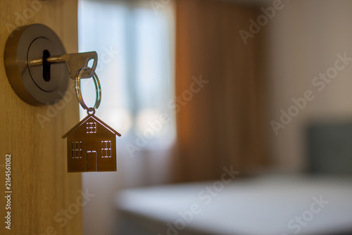 Open door to a new home with key and home shaped keychain. Mortgage, investment, real estate, property and new home concept