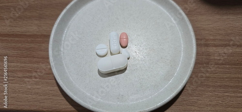 Foto Various types of pills are placed on a white plate, including large white oval, white oval printed with the number 500, white round pills, pink capsule-shaped pills