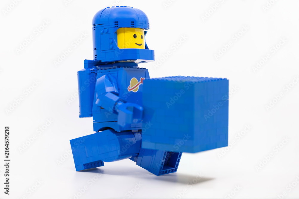 Fototapeta premium Hong Kong, June 8, 2026: A classic blue LEGO spaceman carries a blue brick block, symbolizing a playful gift of building element.
