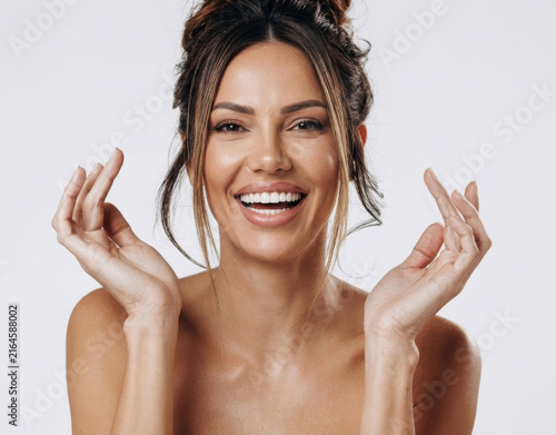 Portrait of a smiling woman posing with hands near face on a white background