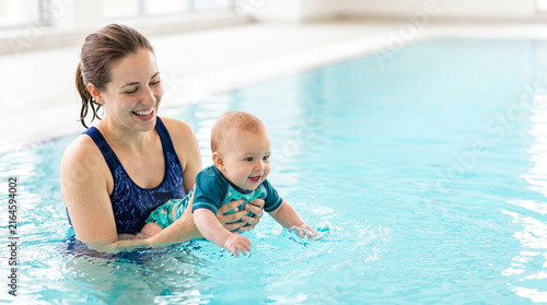 Mother and baby attending infant swimming class as water familiarization and early swimming concept
