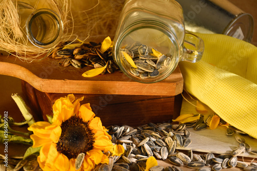 фотографія Sunflower seeds spilling from jar on wooden board