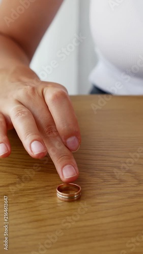 Woman touching wedding ring on table contemplating divorce and end of marriage.