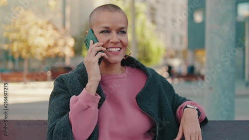 Joyful Woman with Buzz Cut Chats on Smartphone Outdoors