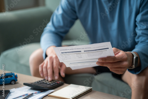 Foto Male hands holding bank payment due notice paper while using calculator to revie
