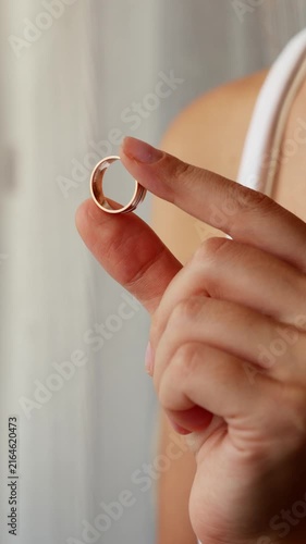 Woman holding removed wedding ring after taking it off, divorce, separation and end of marriage concept.
