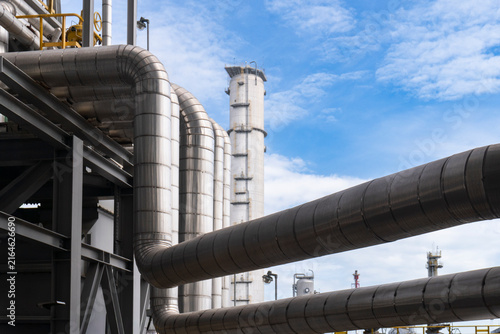Konstfotografi Large insulated pipelines and distillation columns lined up against a blue sky at a petrochemical plant with steel structures and complex pipe racks in an industrial energy facility