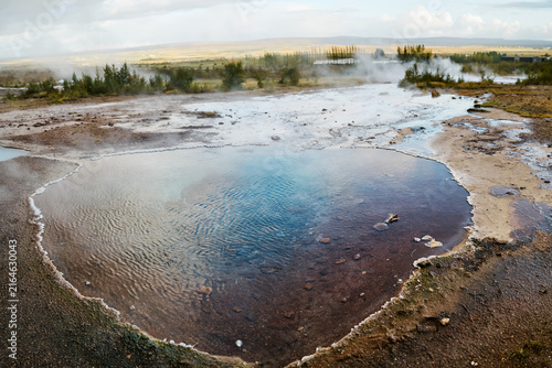 Geothermal hot spring with rising steam in Iceland's natural landscape