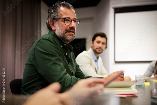 Mature male manager talking to his team during meeting in conference room