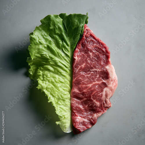 Creative split composition pairing a fresh green lettuce leaf with a raw beef steak on a neutral gray surface, representing nutrition, diet choices and food contrast.