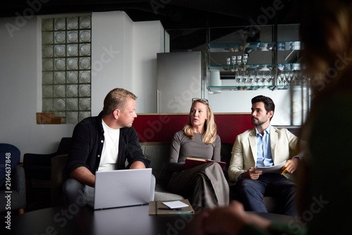 Businesswoman discussing strategy with male colleagues while sitting on sofa