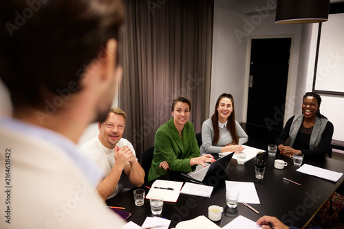 Happy business professionals sharing ideas during meeting in board room