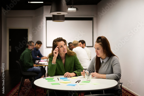 Thoughtful businesswoman sitting with her female colleague in office meeting room