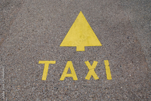 Yellow taxi sign and directional arrow painted on asphalt road surface