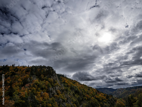 Autumn Forested Cliffs Under Dramatic Cloudy Sky