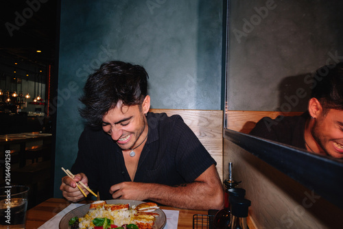 Young man laughing while enjoying a meal out