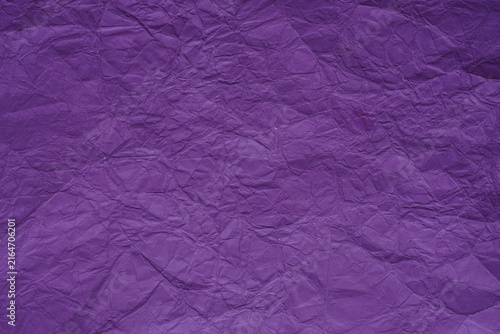 Crumpled purple paper texture with detailed folds, creases, ridges, and natural light and shadow across the surface, creating an abstract textured background