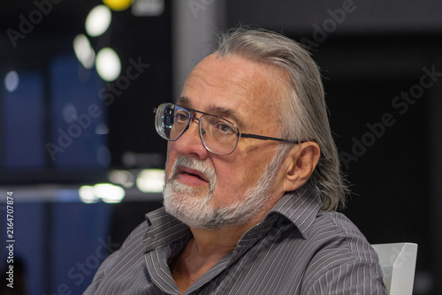 Cuadro en lienzo Thoughtful elderly man with glasses listening in a dim indoor setting