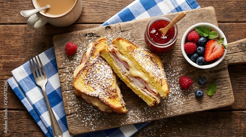 Monte Cristo sandwich with ham and cheese served with fresh berries and jam on wood board perfect for National Monte Cristo Day