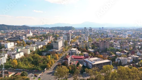 Urban landscape of Ljubljana, Slovenia with buildings and hills under a sunny sky.