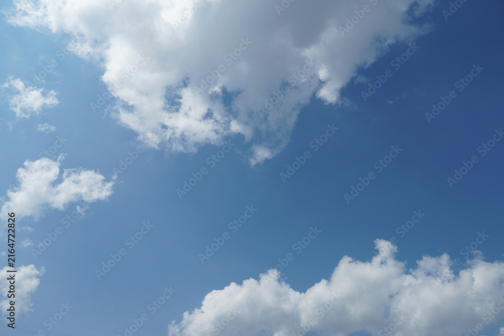 Fototapeta premium White fluffy clouds in the sky. Blue sky and cloud cover on a sunny summer day. Empty background, copy space