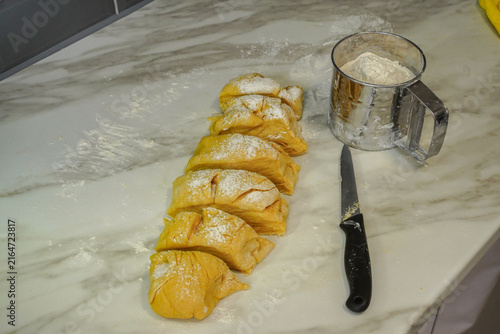 Fotografía Portioned dough pieces on marble countertop with flour sifter and knife