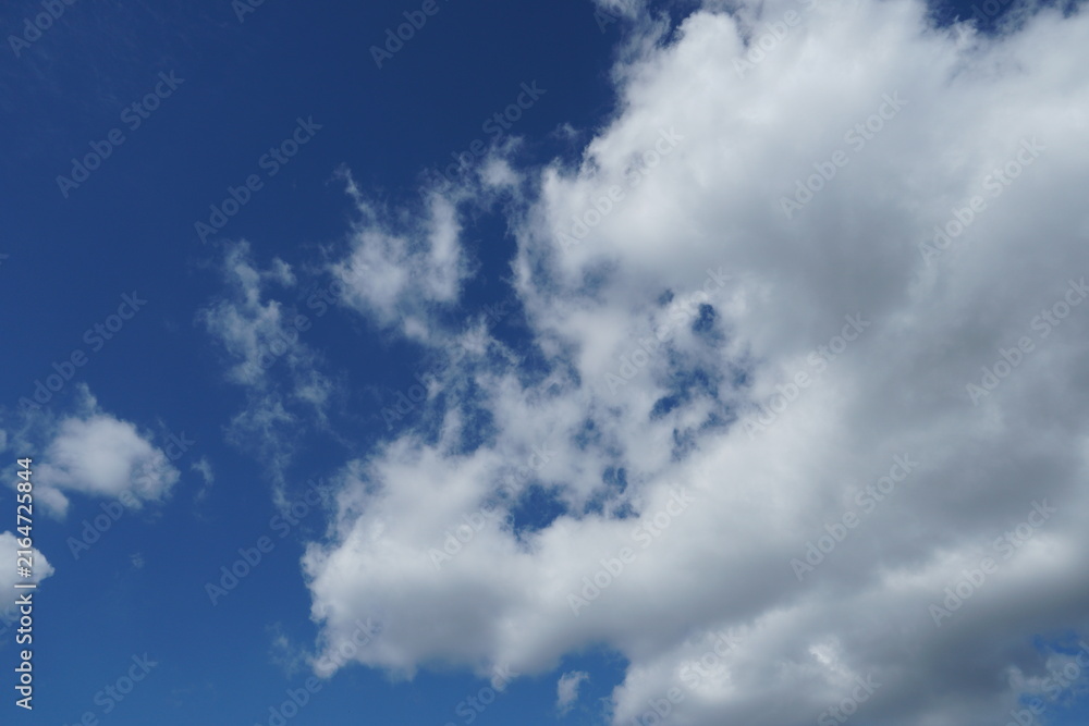 Obraz premium White fluffy clouds in the sky. Blue sky and cloud cover on a sunny summer day. Empty background, copy space