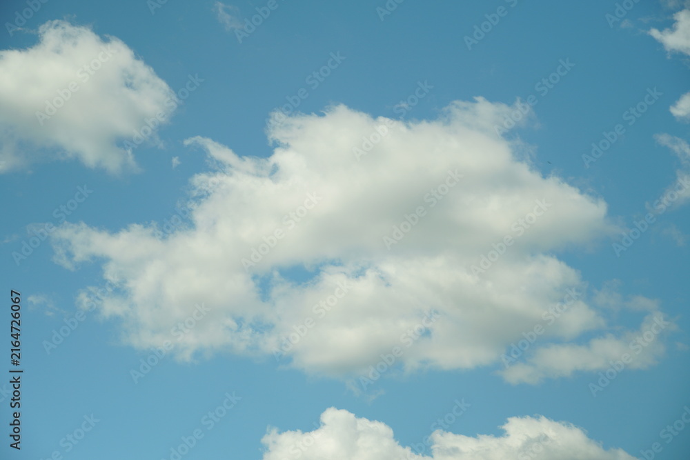 Obraz premium White fluffy clouds in the sky. Blue sky and cloud cover on a sunny summer day. Empty background, copy space