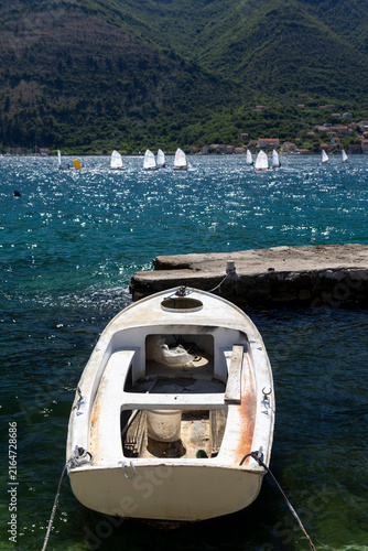 Small White Moored Fishing Boat in Sea Bay with Sailing Boats Background