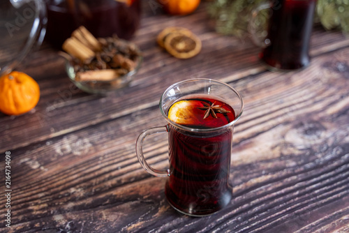 Fotografía Warm glass of homemade mulled wine garnished with star anise served on a rustic wooden table surrounded by cinnamon sticks dried orange slices and festive Christmas decorations